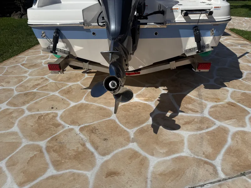 Slide: The Image of 2023 Robalo R222 boat stern with outboard motor on stone-patterned driveway. - 13