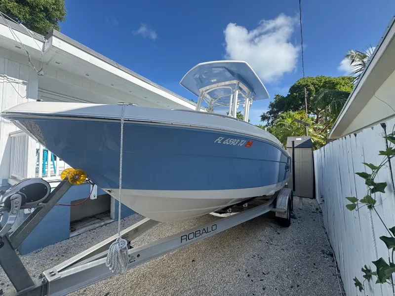 Slide: The Image of 2023 Robalo R222 boat on trailer, parked outdoors under clear blue sky. - 2