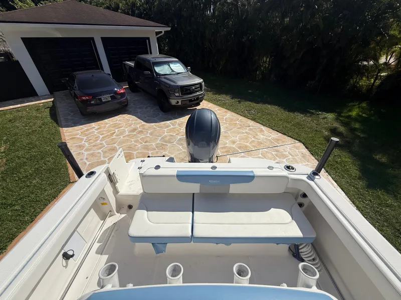 Slide: The Image of 2023 Robalo R222 boat parked in driveway with two cars, viewed from above. - 23