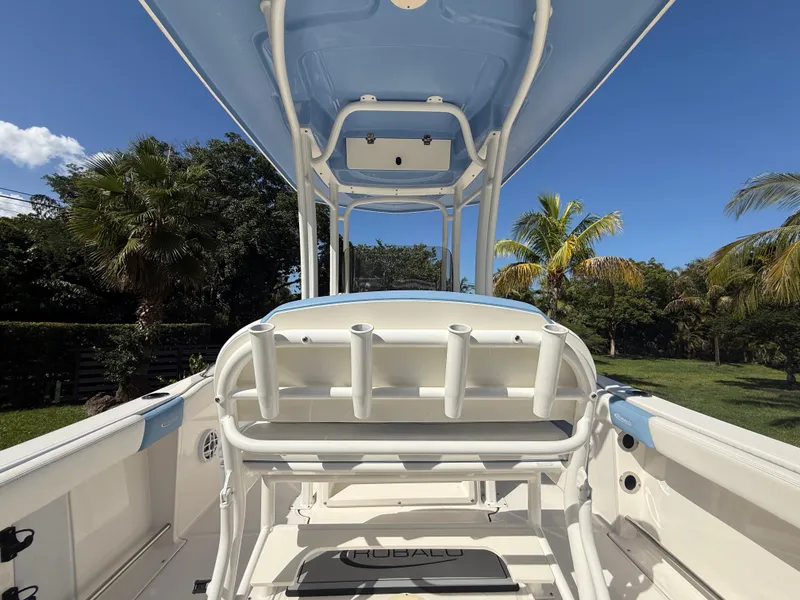 Slide: The Image of 2023 Robalo R222 boat interior with rod holders, blue canopy, and lush greenery background. - 24