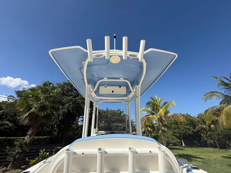 Slide: The Image of 2023 Robalo R222 boat with T-top against a clear blue sky and palm trees. - 25