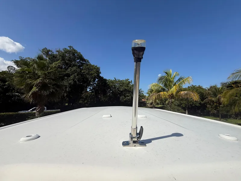 Slide: The Image of 2023 Robalo R222 boat deck with navigation light, surrounded by palm trees and clear blue sky. - 29