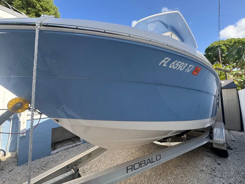 Slide: The Image of 2023 Robalo R222 boat on trailer, blue hull, parked outdoors. - 3