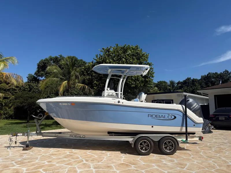 Slide: The Image of 2023 Robalo R222 boat on trailer, parked outdoors under clear blue sky. - 4