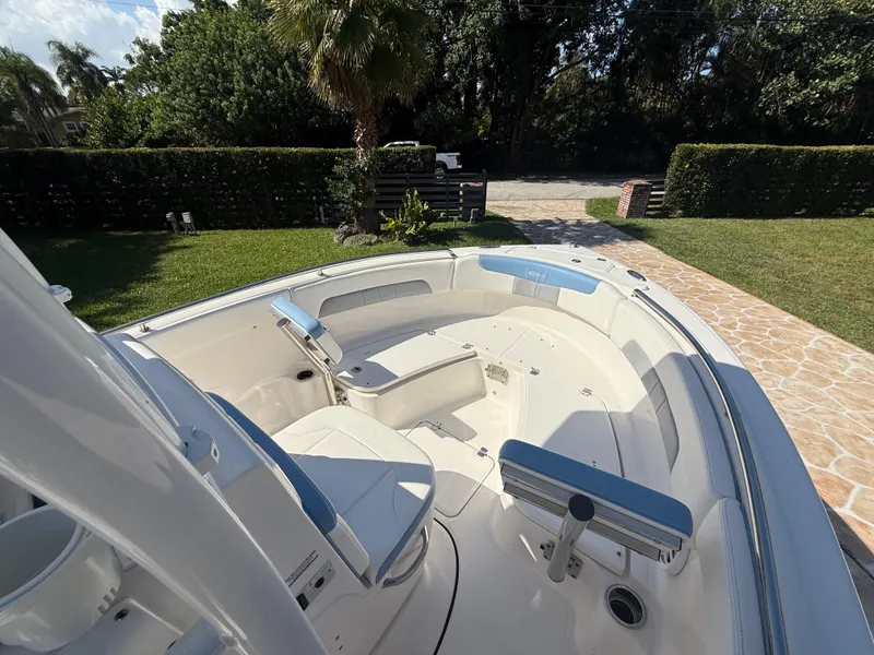 Slide: The Image of 2023 Robalo R222 boat interior with seating, set in a lush garden background. - 49