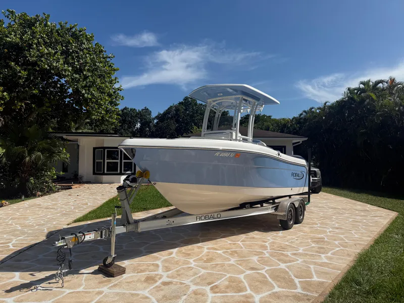 Slide: The Image of 2023 Robalo R222 boat on trailer in sunny driveway setting. - 5
