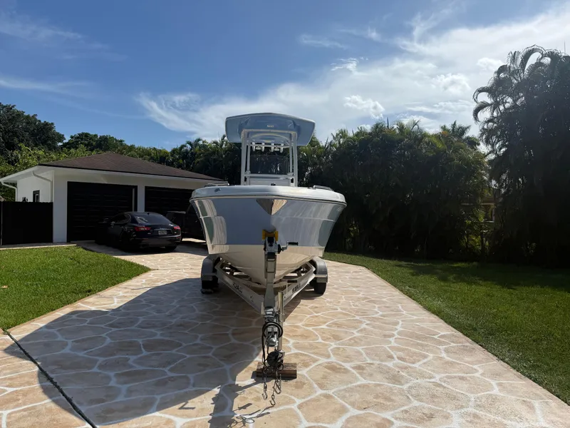 Slide: The Image of 2023 Robalo R222 boat on trailer in driveway, sunny day, lush greenery background. - 6
