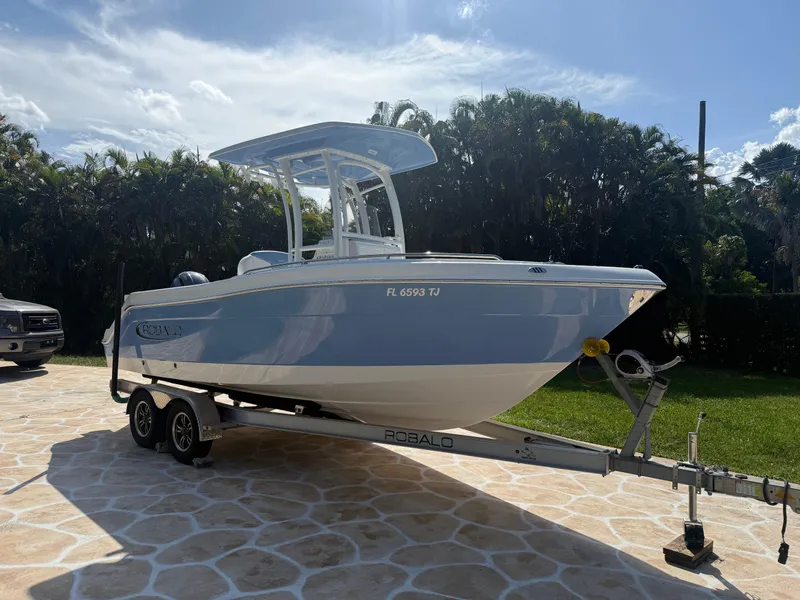 Slide: The Image of 2023 Robalo R222 boat on trailer, parked outdoors under a sunny sky. - 7
