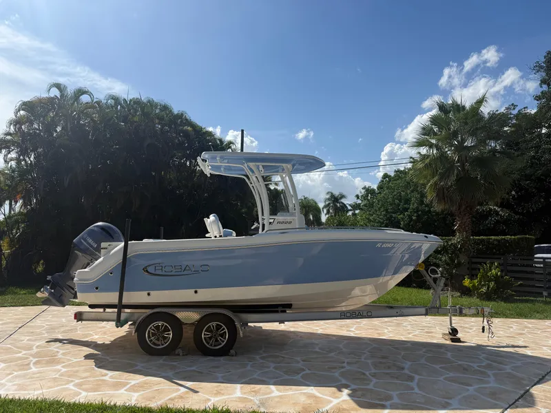 Slide: The Image of 2023 Robalo R222 boat on trailer, parked outdoors under a clear blue sky. - 8