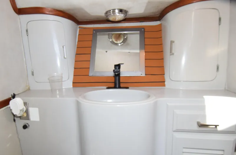 Slide: The Image of 1988 Mediterranean 38 Convertible yacht bathroom with sink, mirror, and storage cabinets. - 20