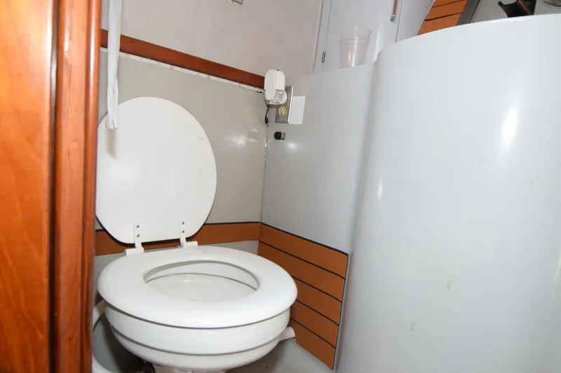 Slide: The Image of 1988 Mediterranean 38 Convertible yacht bathroom with white toilet and wooden accents. - 21