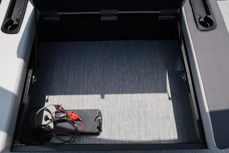 Slide: The Image of Open storage compartment in 2025 Bennington S Swingback 22 SSB boat, featuring wiring and battery. - 22