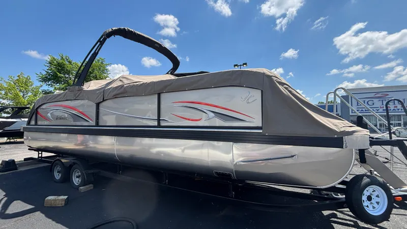 The Image of 2025 JC NEPTOON 27TT SPORT pontoon boat covered, parked on trailer under blue sky. - 1