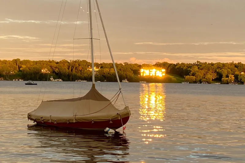 Slide: The Image of Tofinou 7 sailboat on tranquil lake at sunset, reflecting golden light, 1998 model. - 17