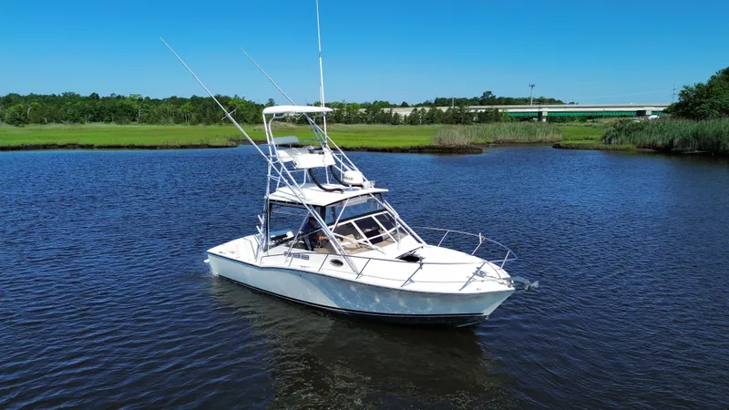 Slide: The Image of 2004 Carolina Classic 28 boat on calm water with lush green shoreline. - 1