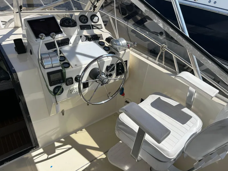 Slide: The Image of 2004 Carolina Classic 28 boat helm with steering wheel, controls, and captain's chair. - 17