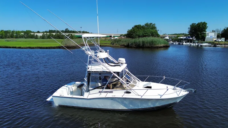 Slide: The Image of 2004 Carolina Classic 28 boat on a calm river with lush green surroundings. - 2