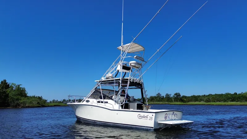 Slide: The Image of 2004 Carolina Classic 28 boat on calm water under clear blue sky. - 5