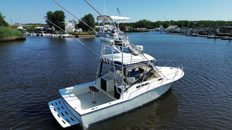 Slide: The Image of 2004 Carolina Classic 28 boat on a calm river, surrounded by greenery and docks. - 7