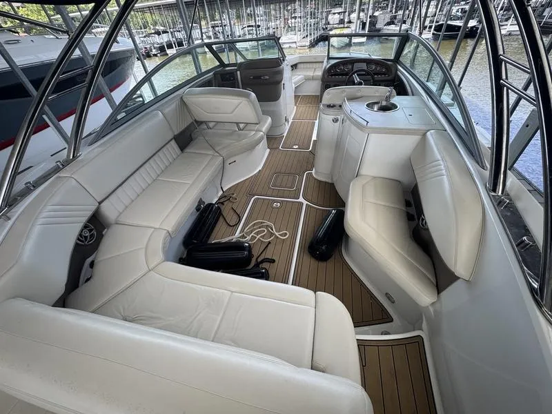 Slide: The Image of 2002 Sea Ray 290 boat interior with white seating and wood flooring, docked at marina. - 1