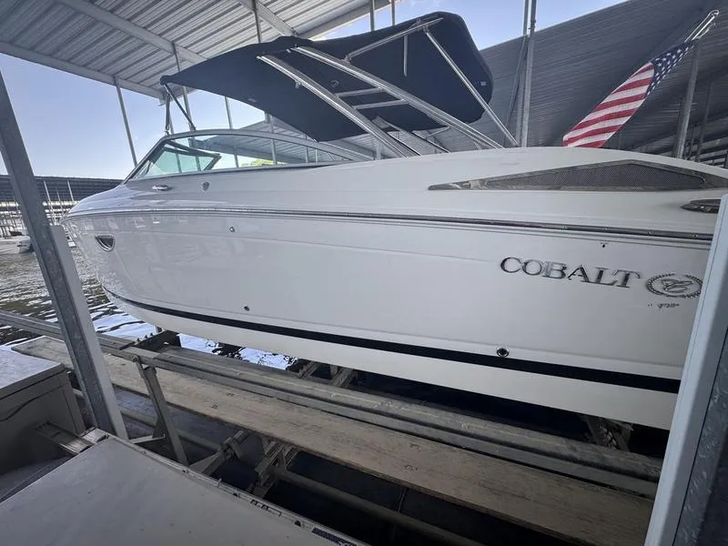 Slide: The Image of White 2002 Sea Ray 290 boat docked under a covered marina with an American flag. - 4