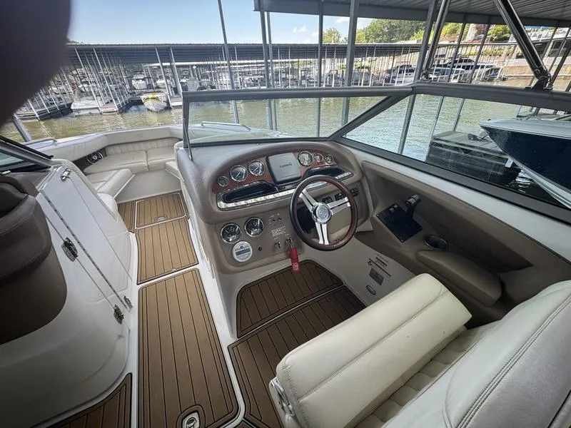 Slide: The Image of 2002 Sea Ray 290 boat cockpit with steering wheel, dashboard, and seating, docked at marina. - 5