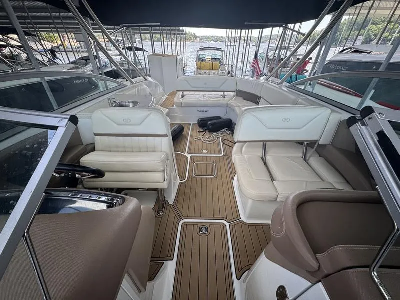 Slide: The Image of 2002 Sea Ray 290 boat interior with beige seating and wood flooring, docked at marina. - 6