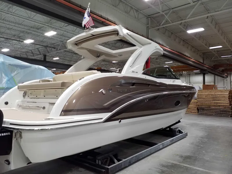 Slide: The Image of 2019 Formula 350 Crossover Bowrider OB in warehouse, sleek design, American flag displayed. - 6
