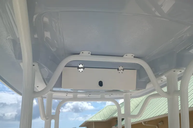 Slide: The Image of 2025 Robalo R230 Center Console T-top with storage compartment, under a clear blue sky. - 16