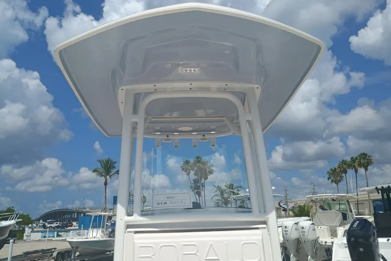 Slide: The Image of 2025 Robalo R230 Center Console boat under a clear blue sky with clouds. - 25