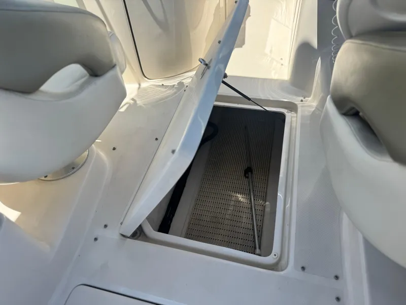 Slide: The Image of 2005 Sea Ray 240 Sundeck interior storage compartment with open hatch between seats. - 22