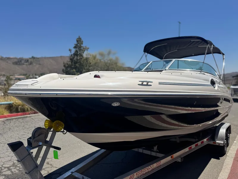 Slide: The Image of 2005 Sea Ray 240 Sundeck boat on trailer, parked outdoors under clear blue sky. - 3