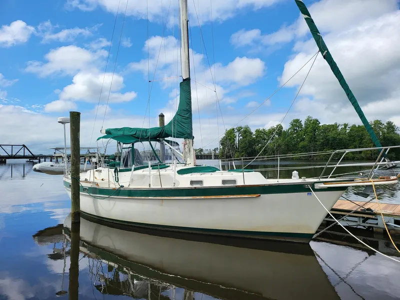 The Image of 1983 Irwin 38 Center Cockpit sailboat docked on a calm, reflective waterway. - 0