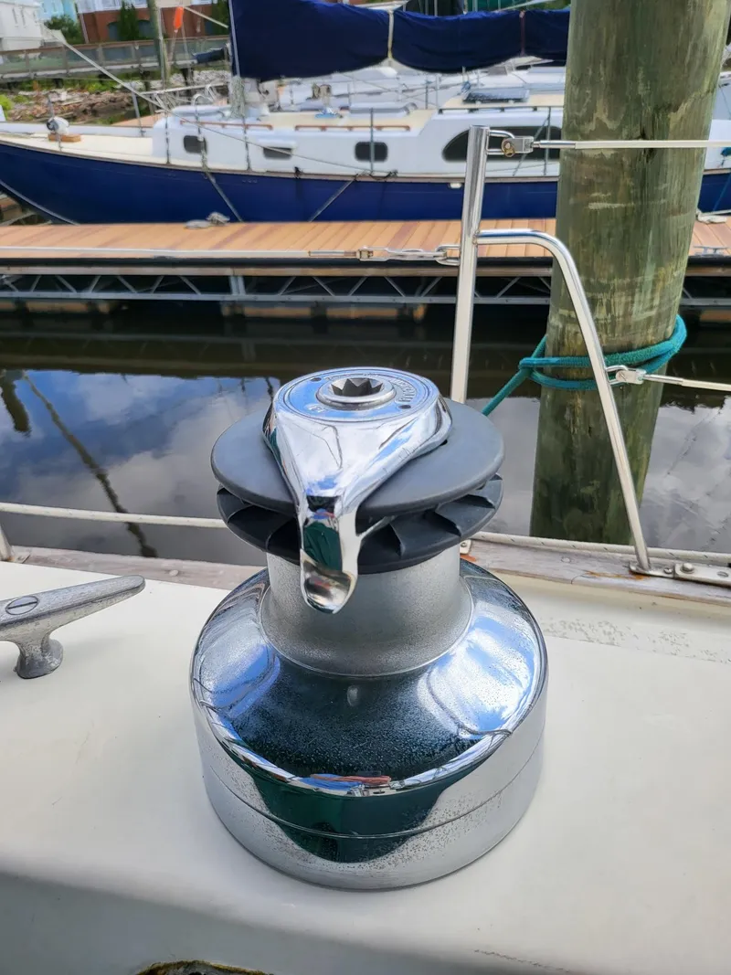 Slide: The Image of Chrome winch on 1983 Irwin 38 Center Cockpit sailboat, docked with other boats in background. - 12