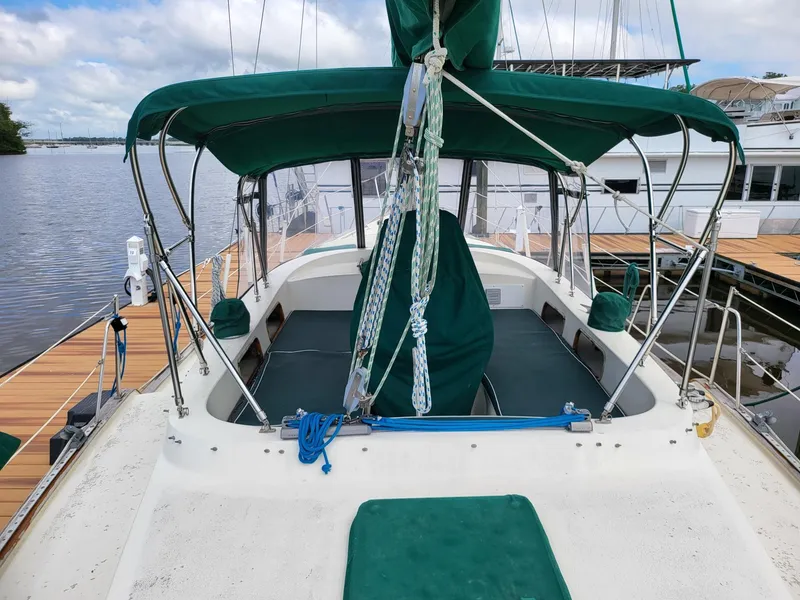 Slide: The Image of 1983 Irwin 38 Center Cockpit sailboat with green canopy docked by the water. - 31