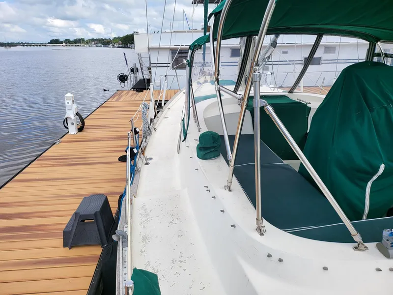 Slide: The Image of 1983 Irwin 38 Center Cockpit sailboat docked, featuring green covers and a wooden pier. - 7