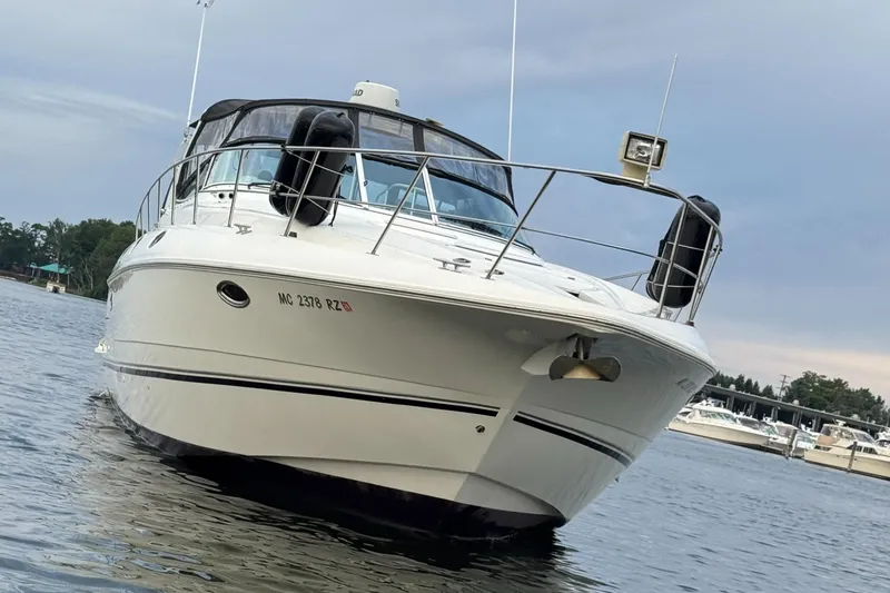 Slide: The Image of 2000 Cruisers Yachts 3870 Express on water, front view, with marina background. - 10