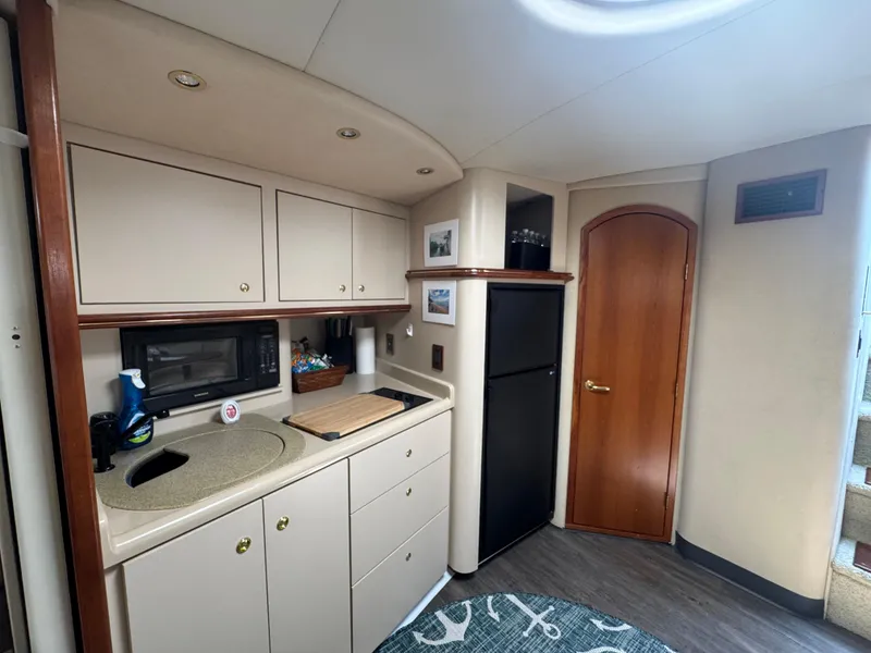Slide: The Image of 2000 Cruisers Yachts 3870 Express interior kitchen with cabinets, sink, and refrigerator. - 28
