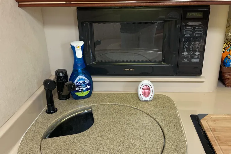 Slide: The Image of Kitchen area in 2000 Cruisers Yachts 3870 Express with microwave and cleaning supplies. - 30