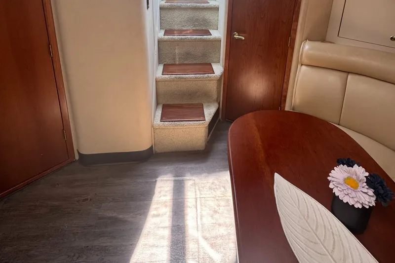 Slide: The Image of Interior of 2000 Cruisers Yachts 3870 Express, featuring stairs, table, and floral decor. - 47