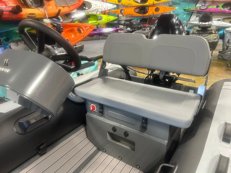 Slide: The Image of 2025 Highfield Classic 310 FCT boat interior with steering wheel and seating, surrounded by colorful kayaks. - 6