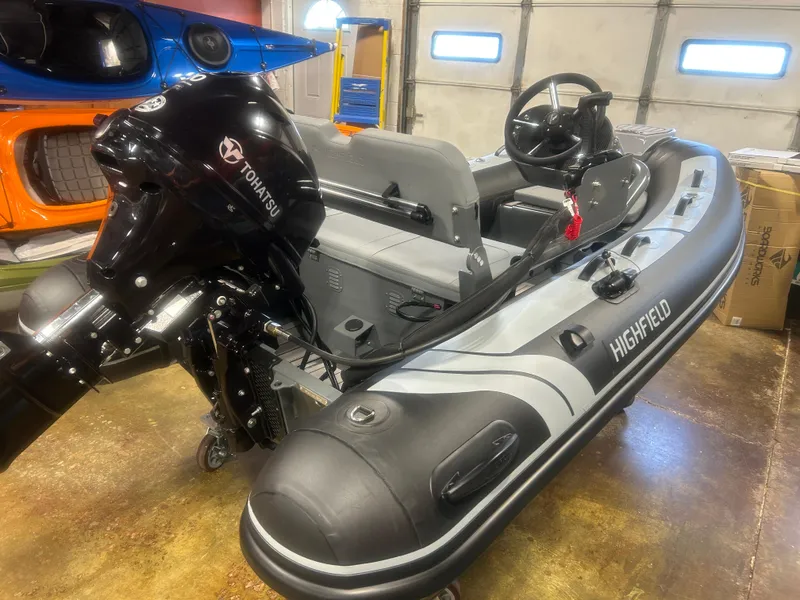Slide: The Image of 2025 Highfield Classic 310 FCT inflatable boat with Tohatsu outboard motor in a garage setting. - 7