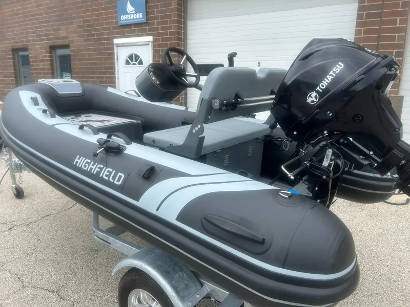 Slide: The Image of 2025 Highfield Classic 310 FCT inflatable boat with Tohatsu engine, parked outside. - 13