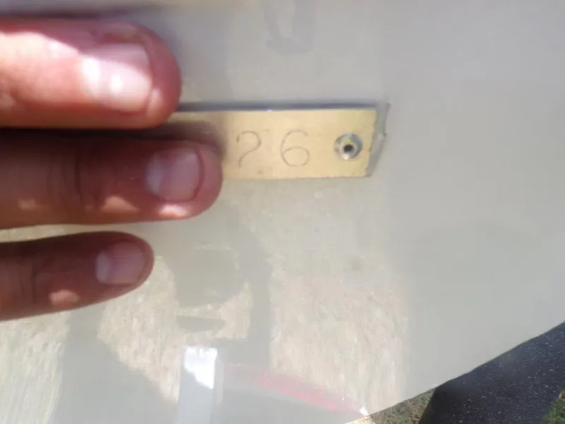 Slide: The Image of Close-up of a hand touching a metal plate with the number "26" on an Xpress XP20CC boat. - 21