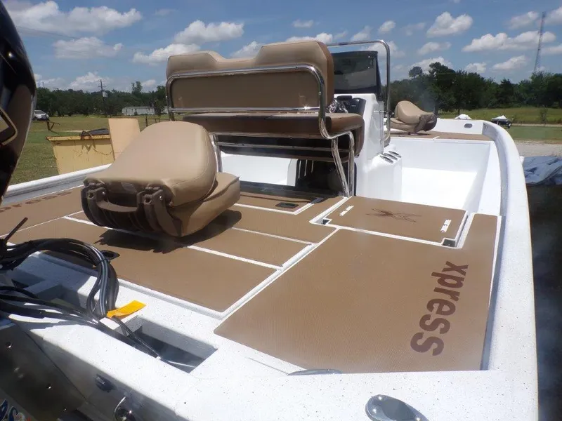 Slide: The Image of 2026 Xpress XP20CC boat interior with tan seating and deck, under a clear sky. - 22