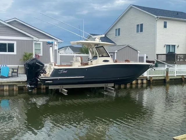 Slide: The Image of 2023 Scout 277 LXF boat docked by waterfront homes. - 0