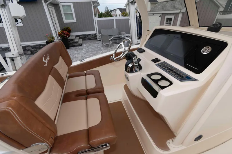 Slide: The Image of 2023 Scout 277 LXF boat interior with brown seating and modern dashboard controls. - 10