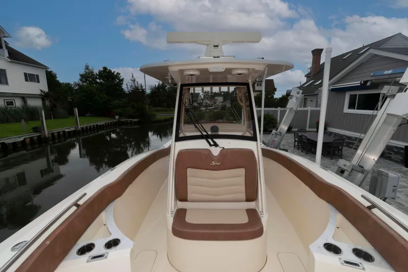 Slide: The Image of 2023 Scout 277 LXF boat docked near waterfront homes under cloudy sky. - 13