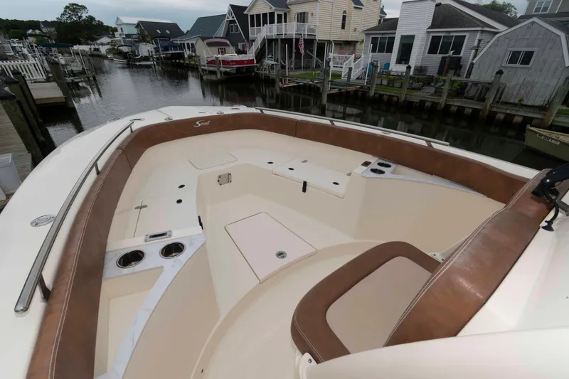 Slide: The Image of 2023 Scout 277 LXF boat interior with brown seating, docked near waterfront homes. - 14