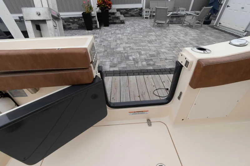 Slide: The Image of 2023 Scout 277 LXF boat interior with open door, brown seating, and patio view. - 16